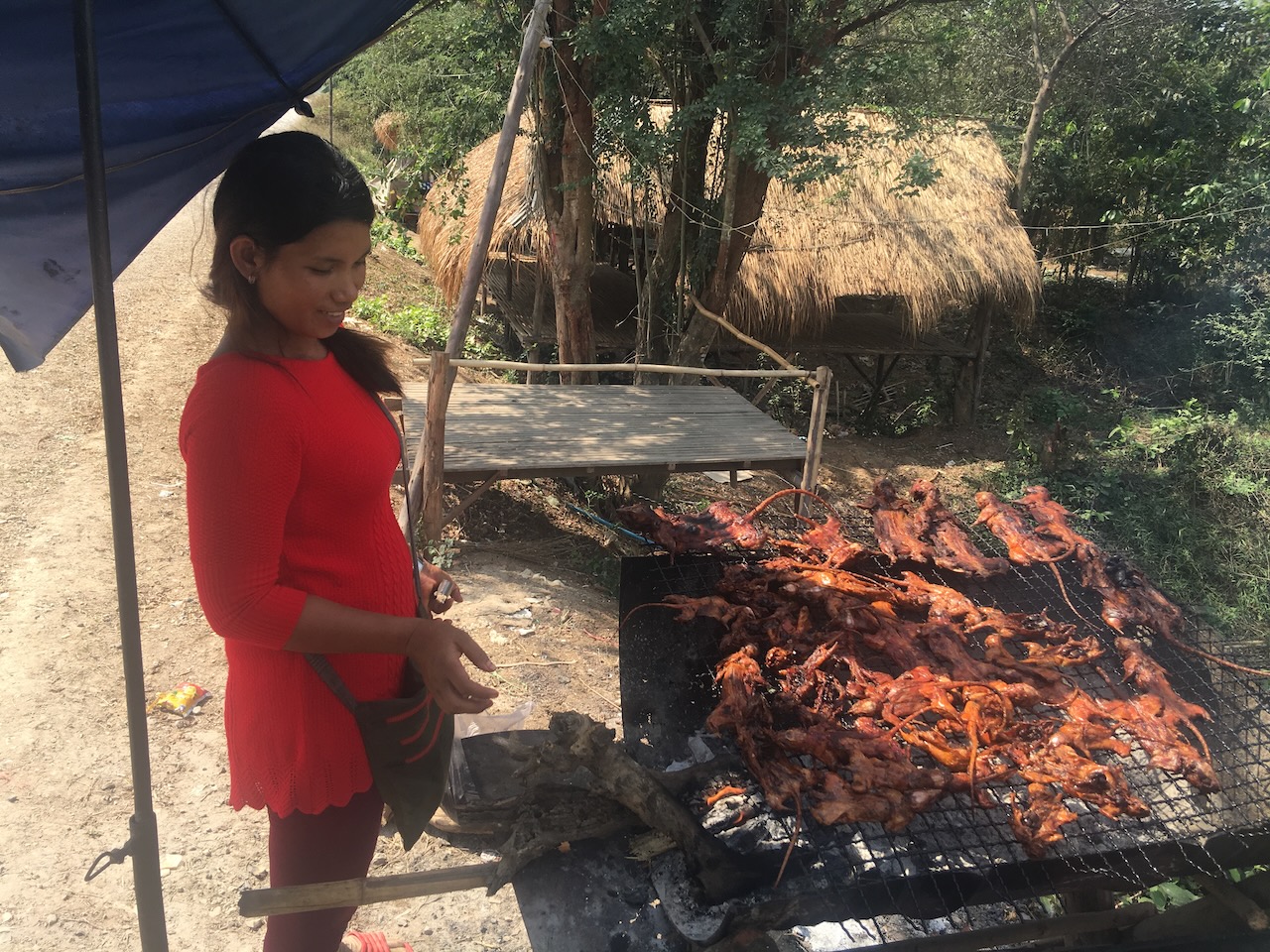 Grilled ricefield rat. The platform and thatched roof hut in the back is where men knock back spirits and enjoy.