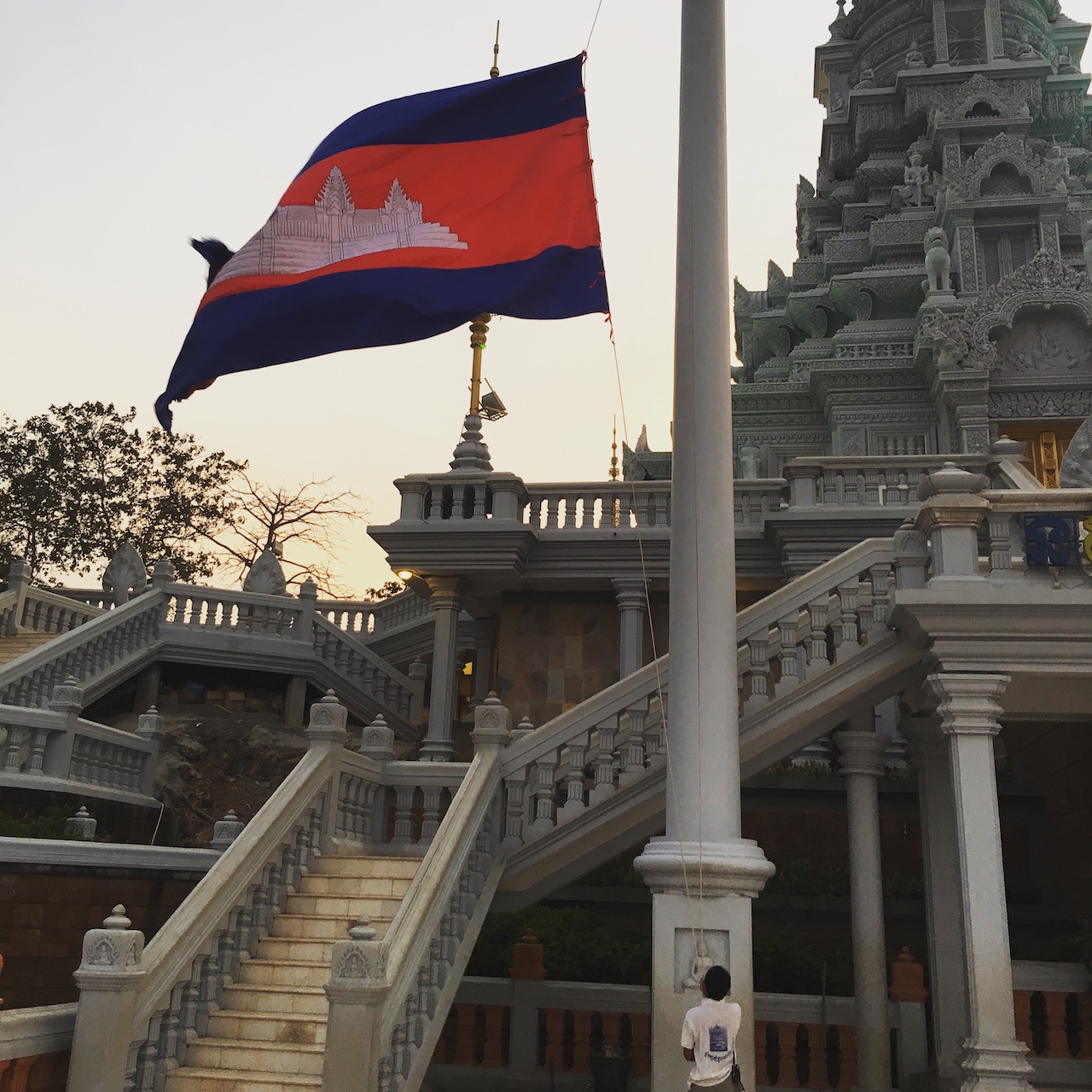 Lowering the ទង់ជាតិកម្ពុជា Tóngchéatĕ Kâmpŭchea [tɔŋciət kampuciə] Cambodian flag at sunset on Phnom Oudong. The Cambodian flag is one of only four state flags (along with Portugal, San Marino, and Spain) to feature a building.